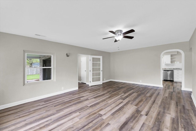 unfurnished living room featuring baseboards, a ceiling fan, dark wood-style floors, and visible vents
