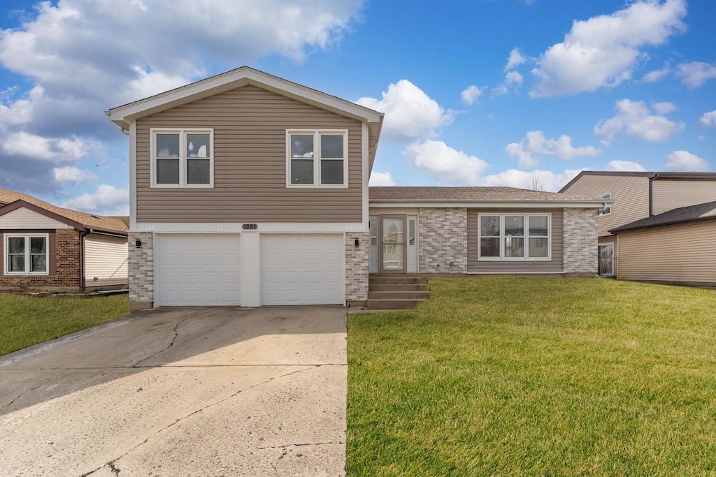 split level home with a front lawn, a garage, brick siding, and concrete driveway