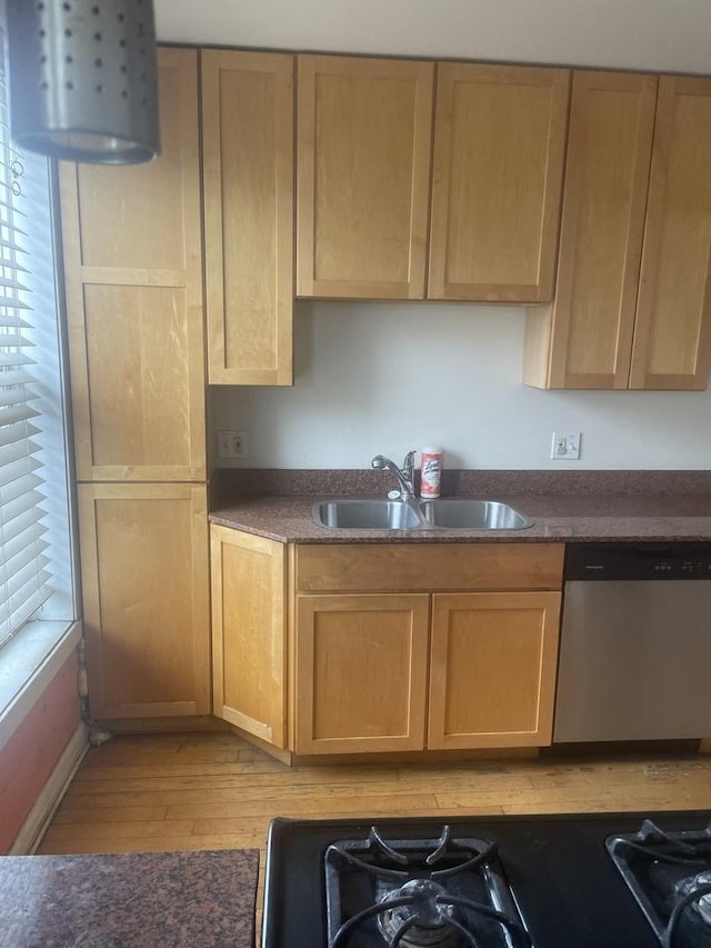 kitchen featuring a wealth of natural light, light wood finished floors, dishwasher, and a sink