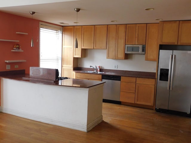 kitchen featuring a sink, dark countertops, appliances with stainless steel finishes, and wood finished floors