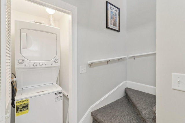 washroom featuring baseboards, stacked washer and clothes dryer, and laundry area