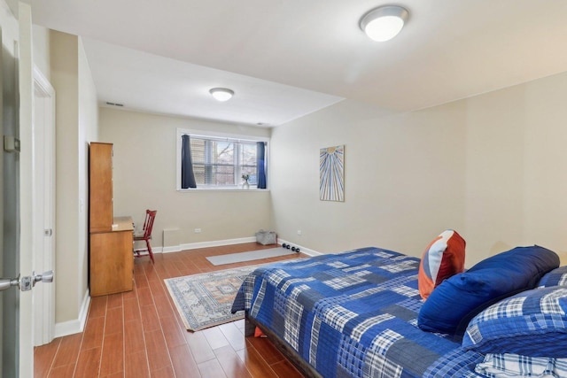bedroom with visible vents, wood finished floors, and baseboards