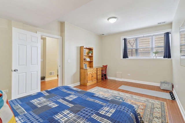 bedroom featuring visible vents, baseboards, and wood tiled floor