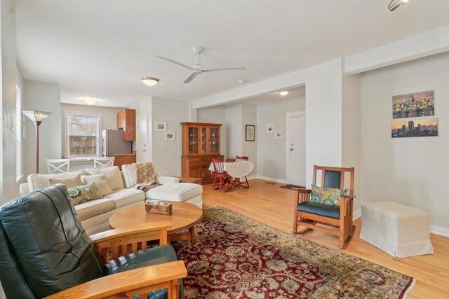living area with baseboards, light wood finished floors, and ceiling fan