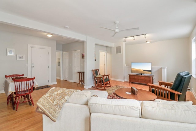 living area featuring baseboards, visible vents, light wood finished floors, and ceiling fan
