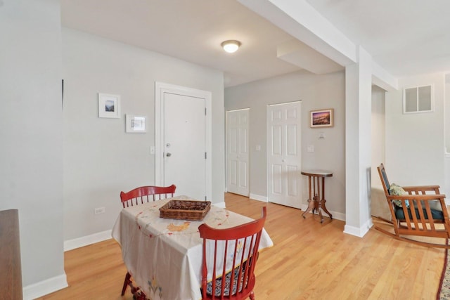 dining room featuring visible vents, baseboards, and light wood finished floors