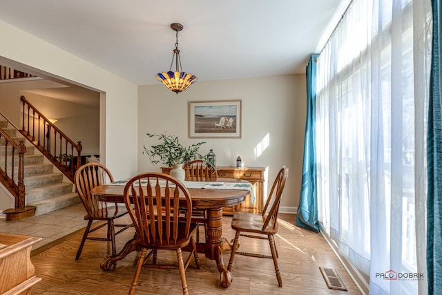 dining area featuring light wood-style floors, stairway, and visible vents