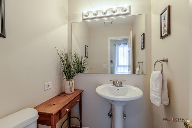 bathroom featuring toilet, a sink, and visible vents