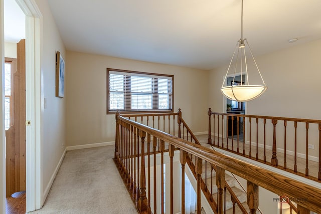 hallway featuring an upstairs landing, baseboards, light carpet, and a wealth of natural light