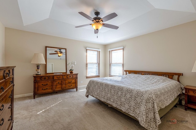 bedroom with baseboards, light colored carpet, ceiling fan, and a raised ceiling