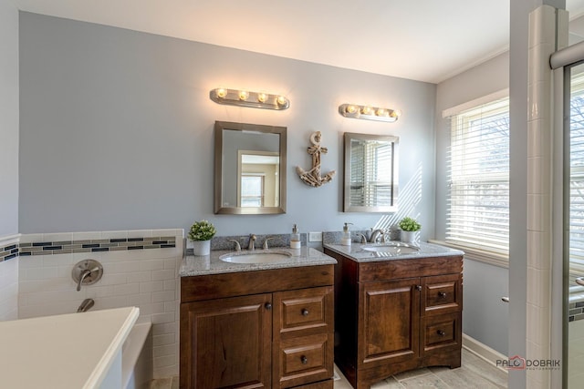 full bathroom featuring tile walls, a sink, two vanities, and a washtub