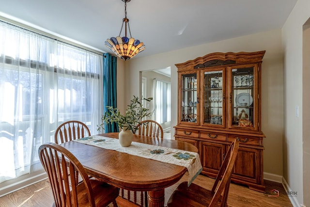 dining space featuring light wood-style flooring and baseboards