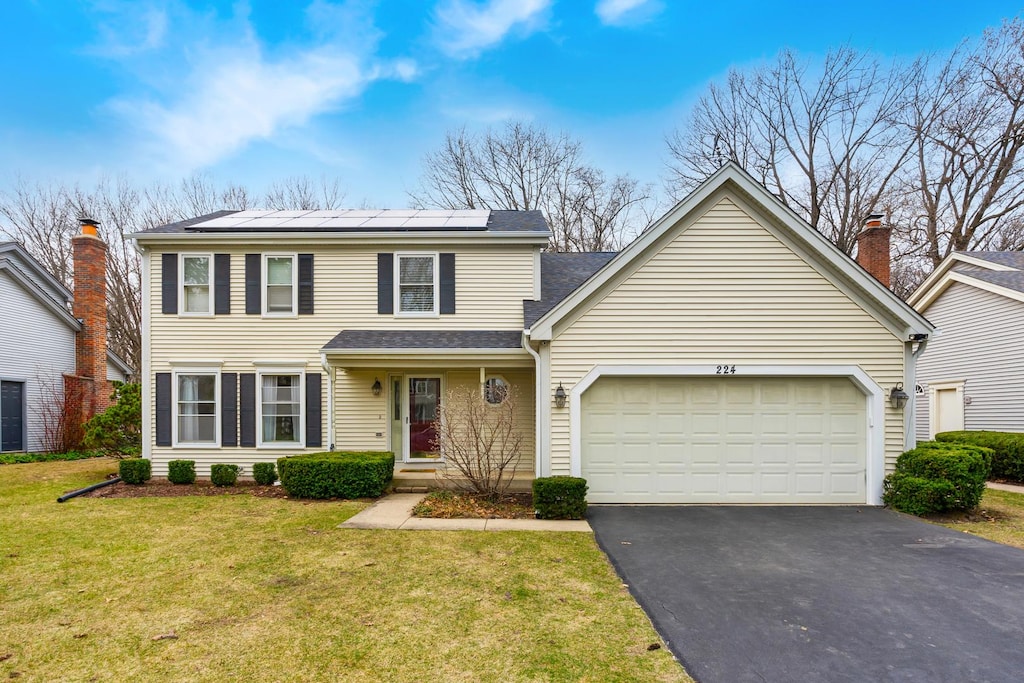 224 Lexington Ave, Fox River Grove, IL 60021 - view of front of home featuring driveway, a front yard, an attached garage, solar panels, and a shingled roof