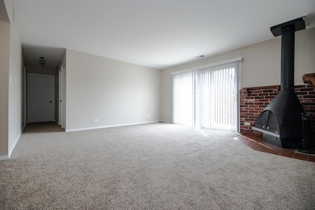 unfurnished living room featuring baseboards, carpet floors, visible vents, and a wood stove