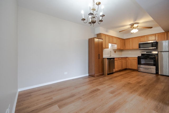 kitchen featuring light countertops, appliances with stainless steel finishes, light wood-style floors, and baseboards