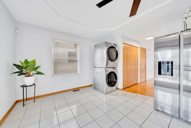 laundry room featuring ceiling fan, laundry area, stacked washer / dryer, baseboards, and light tile patterned flooring