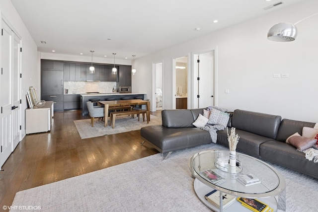 living room with dark wood-type flooring, visible vents, and recessed lighting