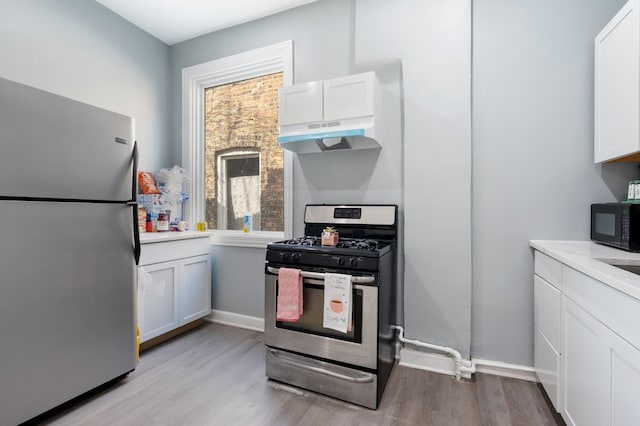 kitchen featuring white cabinetry, light countertops, under cabinet range hood, light wood-style floors, and stainless steel appliances