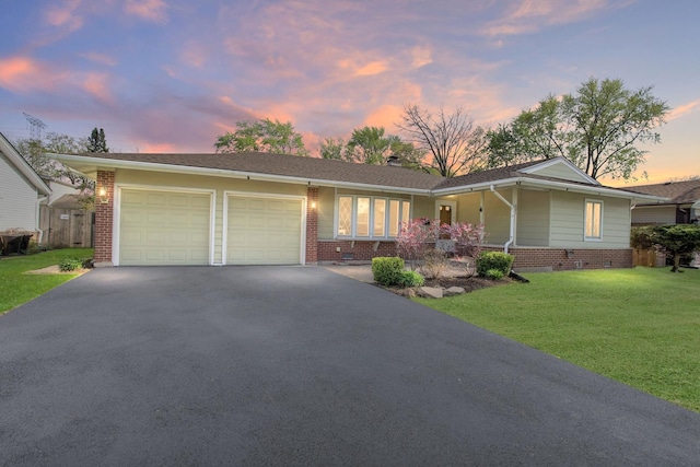 single story home featuring brick siding, an attached garage, asphalt driveway, and a yard