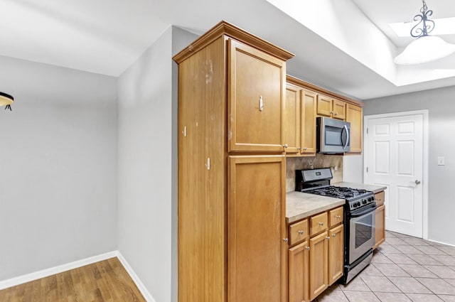 kitchen with appliances with stainless steel finishes, light countertops, baseboards, and backsplash