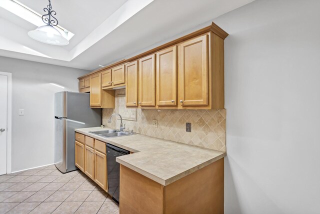kitchen featuring a sink, dishwasher, backsplash, light countertops, and freestanding refrigerator