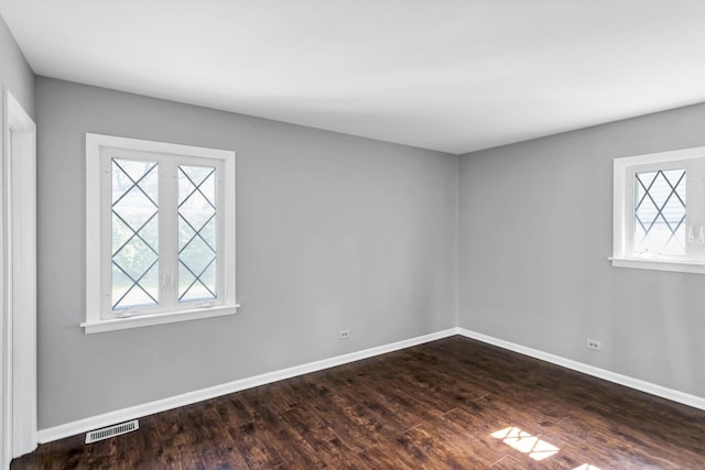 empty room with plenty of natural light, dark wood-style floors, and baseboards