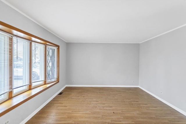 spare room with ornamental molding, wood finished floors, and baseboards