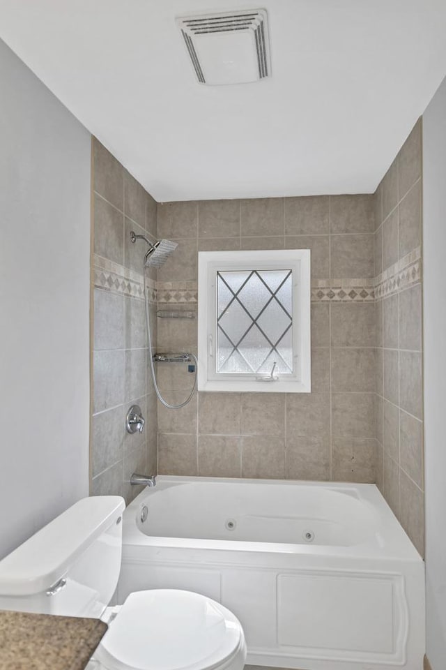 bathroom featuring toilet and a combined bath / shower with jetted tub