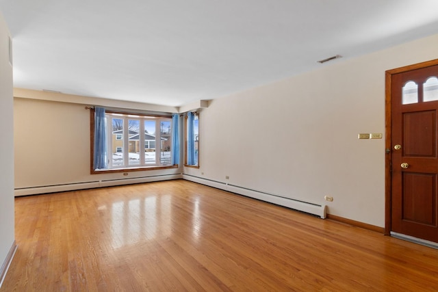 interior space featuring baseboard heating, baseboards, visible vents, a baseboard radiator, and wood finished floors