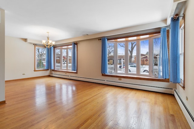 empty room featuring a chandelier, a baseboard radiator, wood finished floors, and baseboards