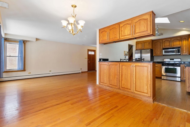 kitchen featuring light wood-style flooring, a baseboard heating unit, dark countertops, stainless steel appliances, and a notable chandelier