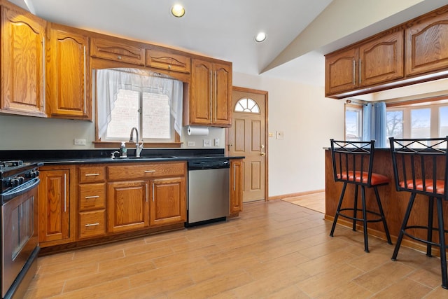 kitchen featuring brown cabinetry, dishwasher, a sink, and range with gas stovetop