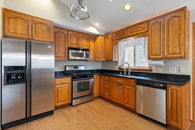 kitchen featuring dark countertops, brown cabinets, a sink, and appliances with stainless steel finishes