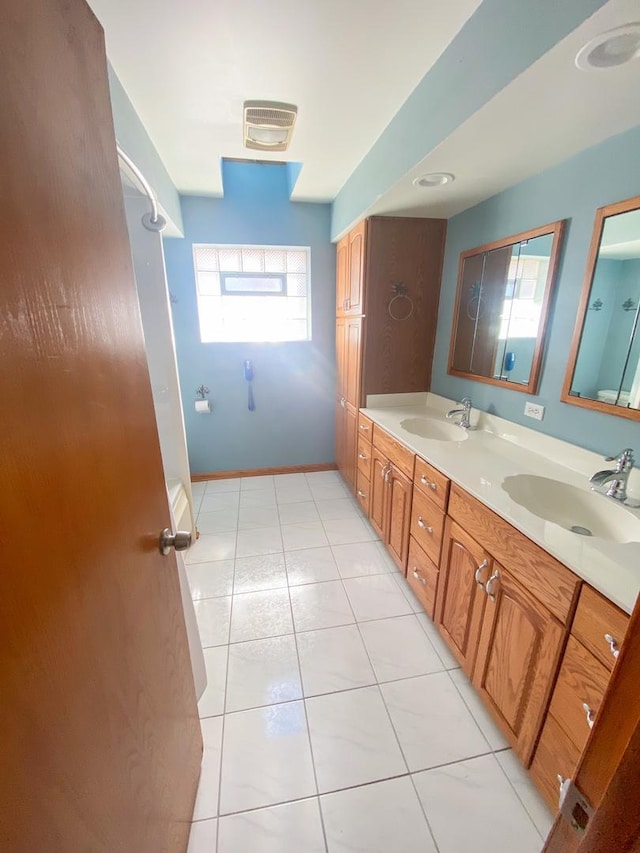 bathroom with tile patterned floors, double vanity, a sink, and baseboards