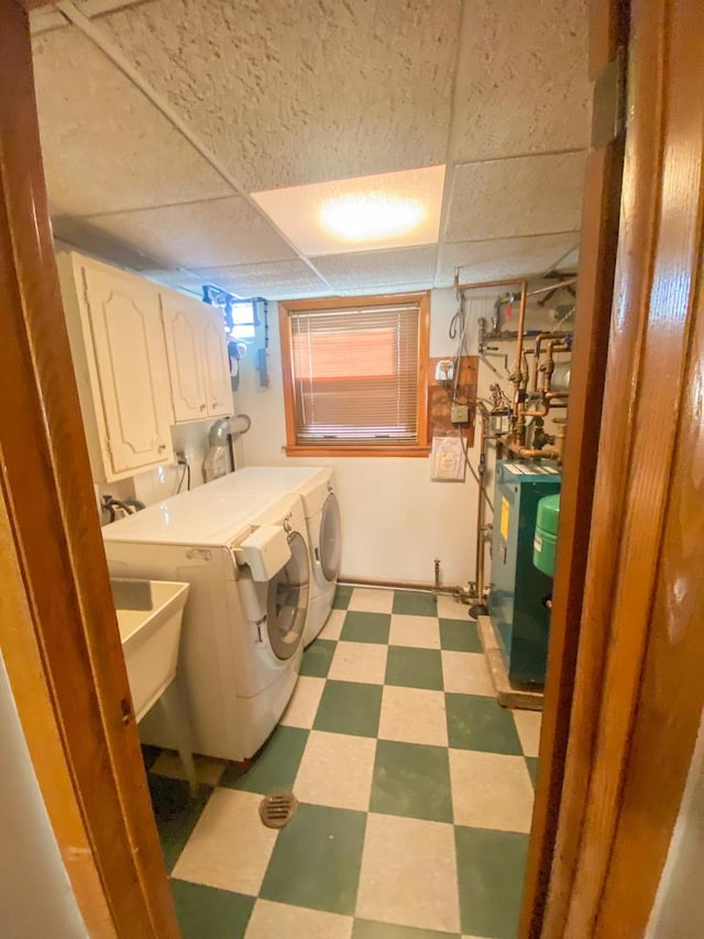 washroom with cabinet space, a heating unit, washing machine and dryer, and light floors