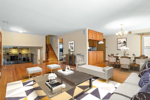 living area featuring a chandelier, stairway, and light wood-type flooring