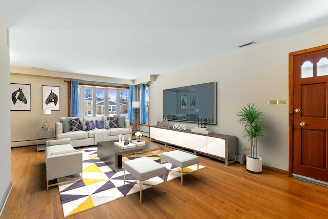 living room with visible vents, a baseboard radiator, baseboards, and wood finished floors