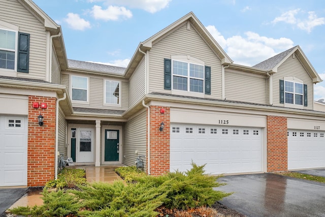 multi unit property featuring a garage, brick siding, and aphalt driveway