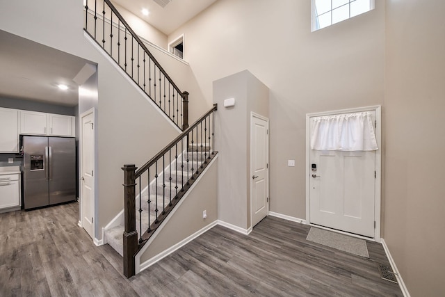 entryway featuring wood finished floors, baseboards, and a towering ceiling