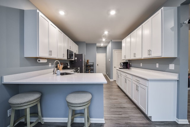 kitchen featuring a sink, a peninsula, appliances with stainless steel finishes, and a breakfast bar