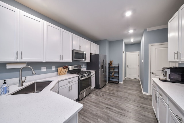 kitchen with a sink, stainless steel appliances, and white cabinets