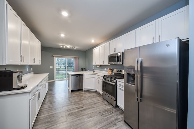 kitchen with white cabinetry, appliances with stainless steel finishes, a peninsula, and light countertops