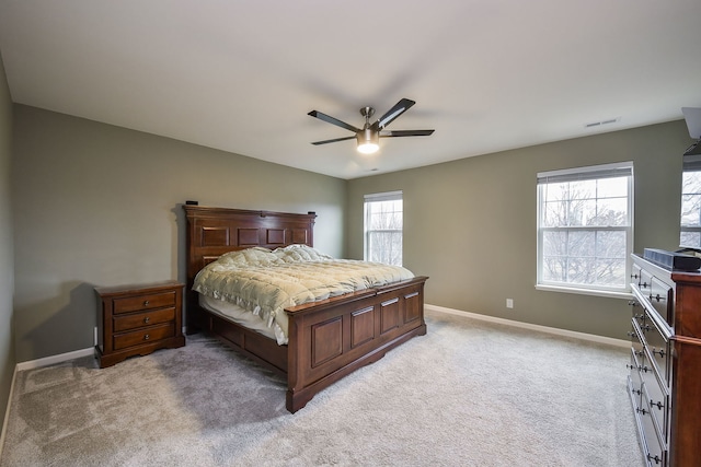 bedroom featuring visible vents, light colored carpet, a ceiling fan, and baseboards