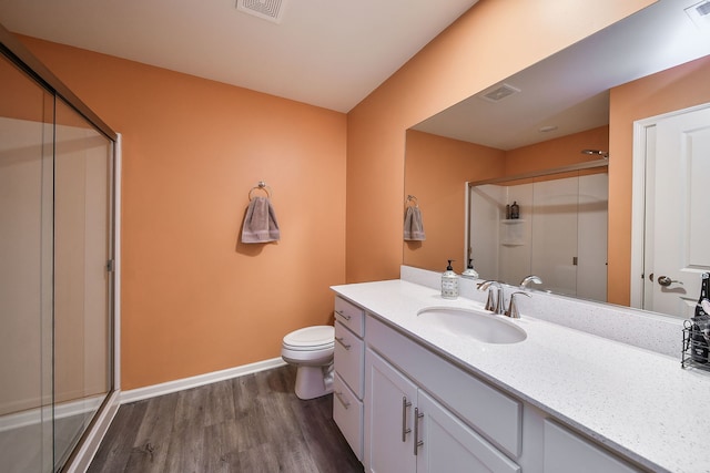 bathroom featuring visible vents, toilet, wood finished floors, a shower stall, and vanity