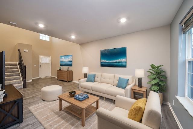 living room featuring a healthy amount of sunlight, baseboards, stairway, recessed lighting, and wood finished floors