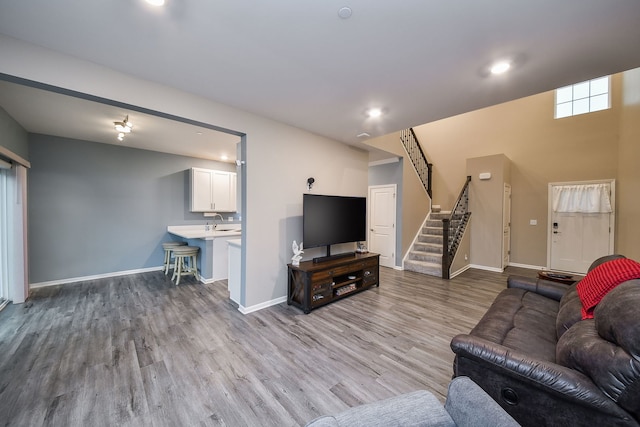 living area featuring stairway, recessed lighting, baseboards, and light wood-style floors