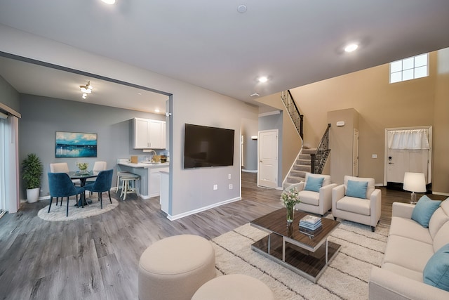 living room with stairs, recessed lighting, light wood-style floors, and baseboards