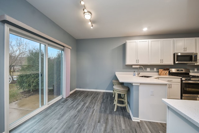 kitchen featuring white cabinets, baseboards, appliances with stainless steel finishes, and a sink