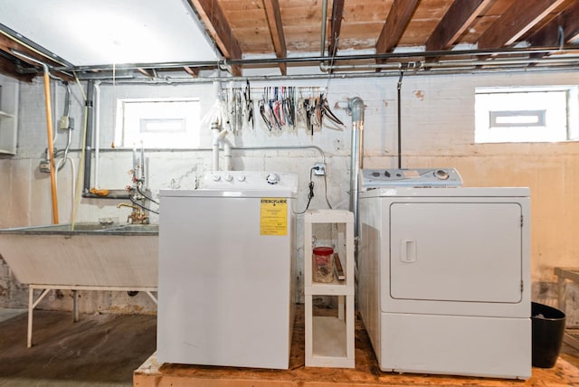 clothes washing area featuring a sink, separate washer and dryer, and laundry area