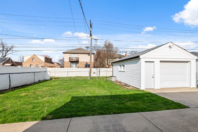 view of yard featuring an outdoor structure, a detached garage, fence, and aphalt driveway